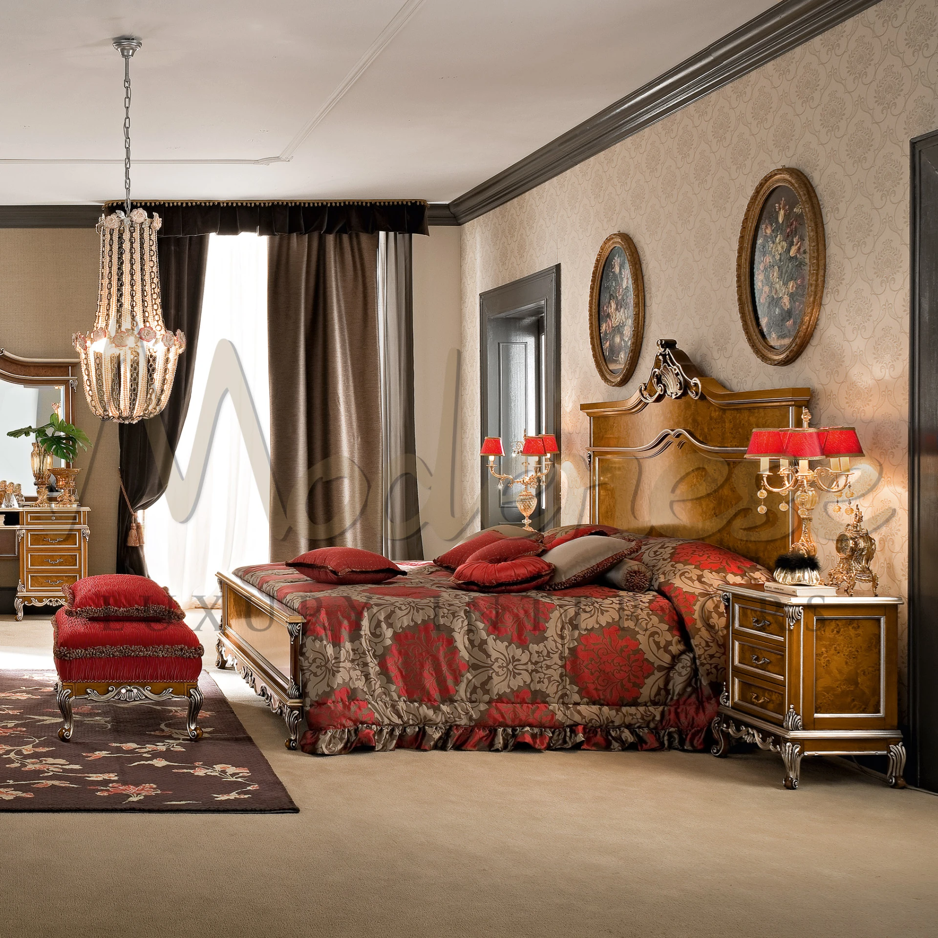 Spacious bedroom with classic design featuring a burl wood bed with red and gold damask bedding, elegant chandelier, heavy drapes, and framed floral paintings on the wall.