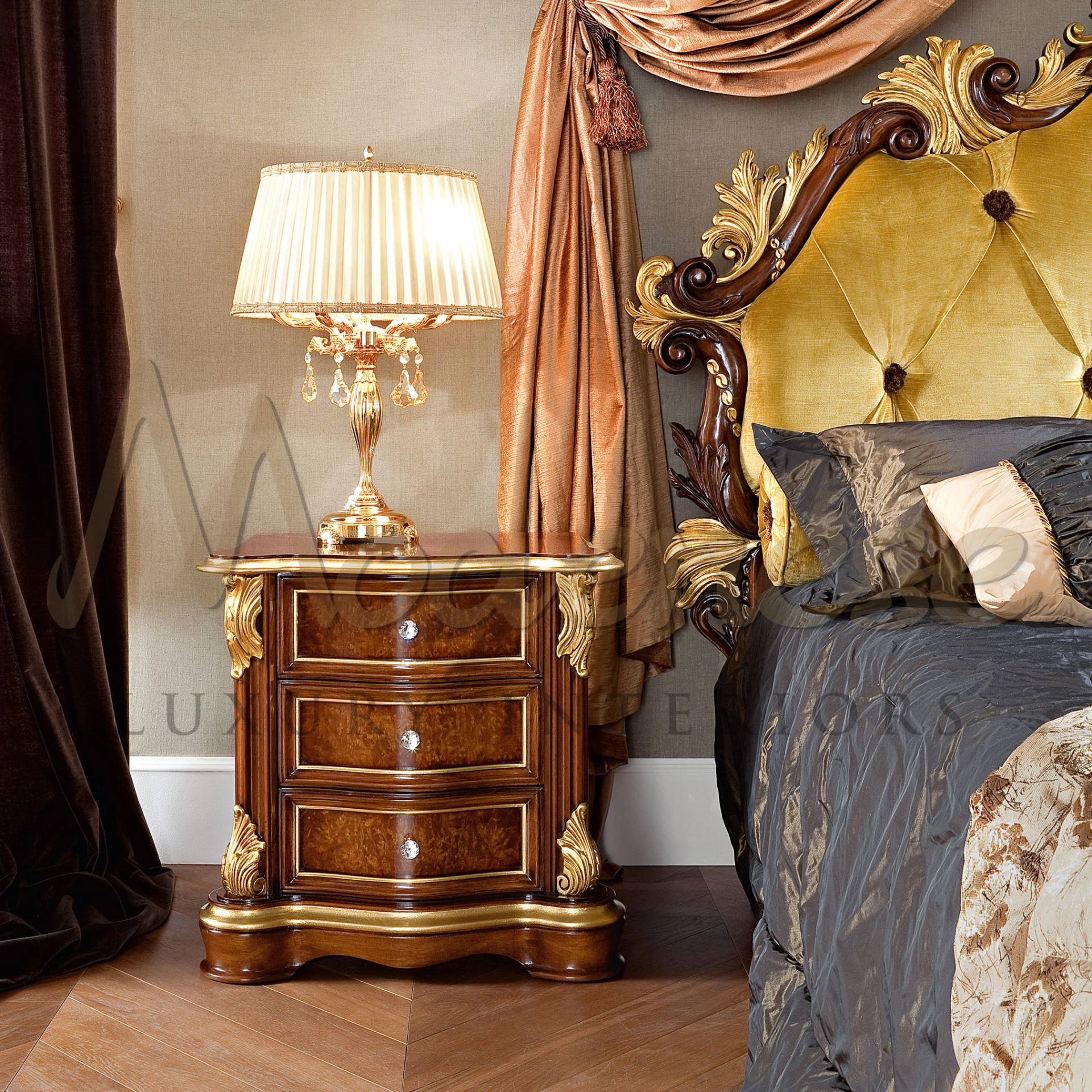 Classic bedroom interior with a burl wood nightstand, ornate gold detailing, and a crystal table lamp, next to an opulent bed with a golden upholstered headboard and luxurious drapery.