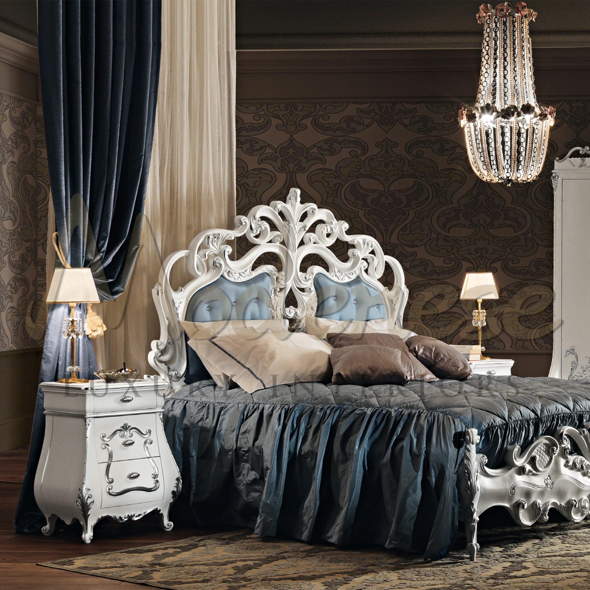 Lavish bedroom interior with a baroque theme, featuring an intricately carved white headboard with plush blue upholstery, complemented by elegant silver nightstands and classic table lamps.