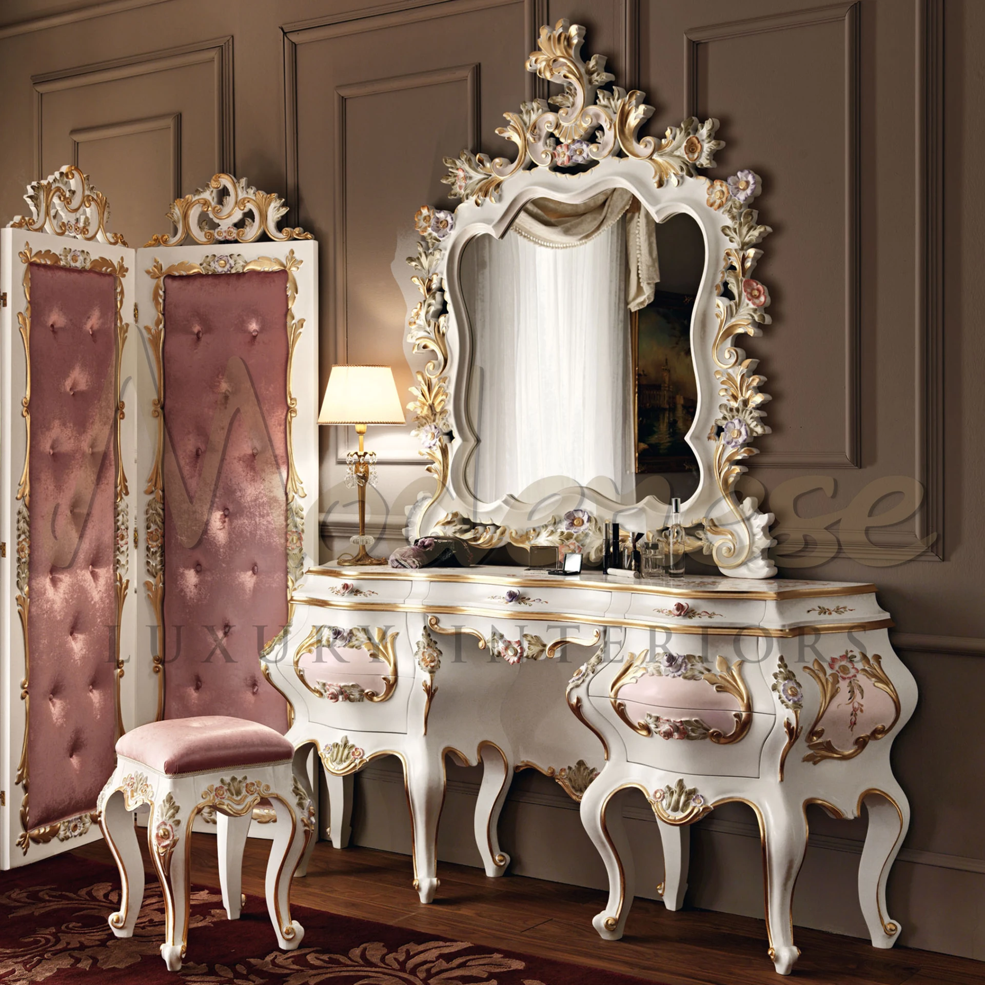 Rococo-style curved dressing table with delicate floral paintings and gilded edges, accompanied by a soft pink stool and various cosmetic items under a warm-hued table lamp.