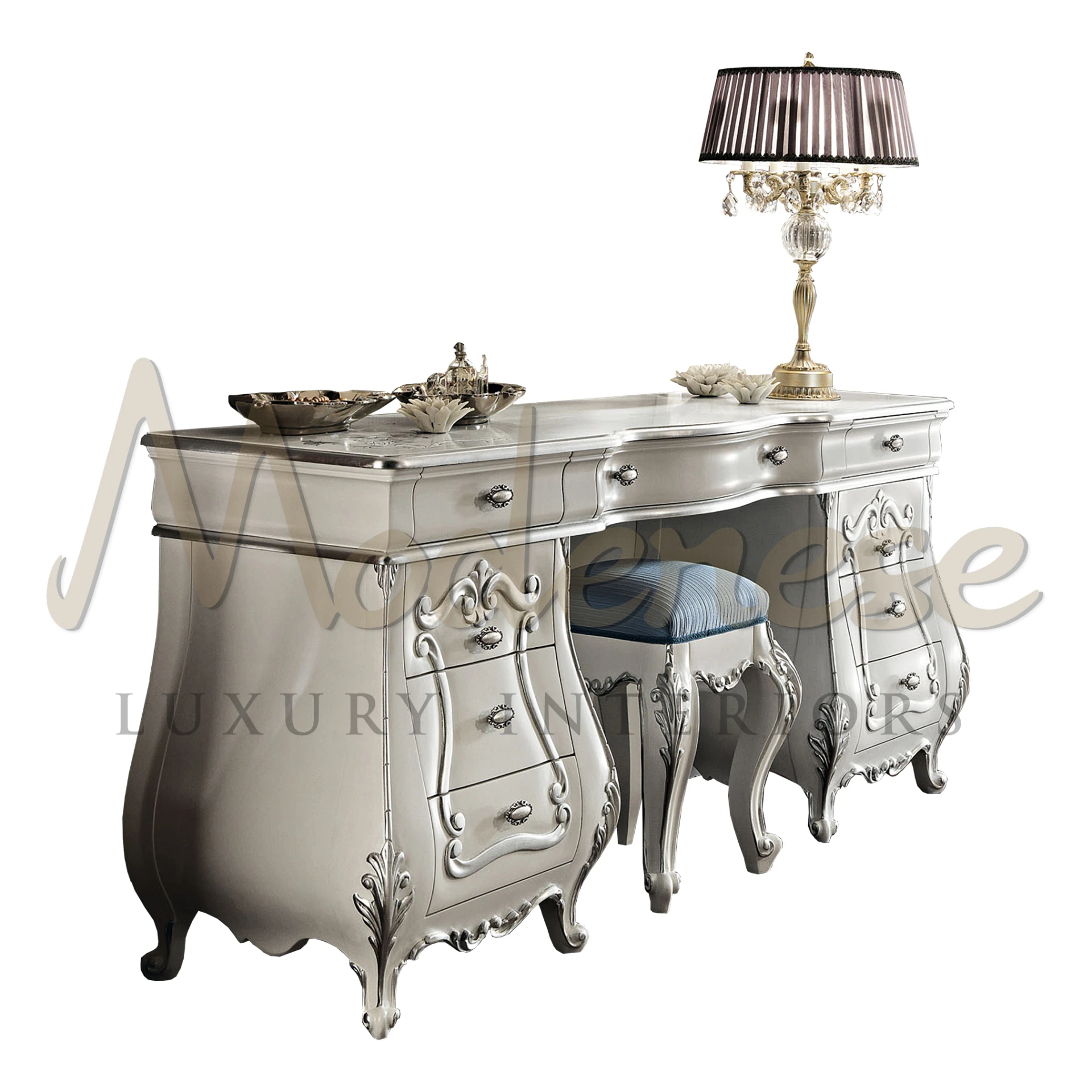 Silver-finished dressing table with baroque details and sculpted legs, accompanied by a blue upholstered stool and an elegant fringed lamp by Modenese Furniture