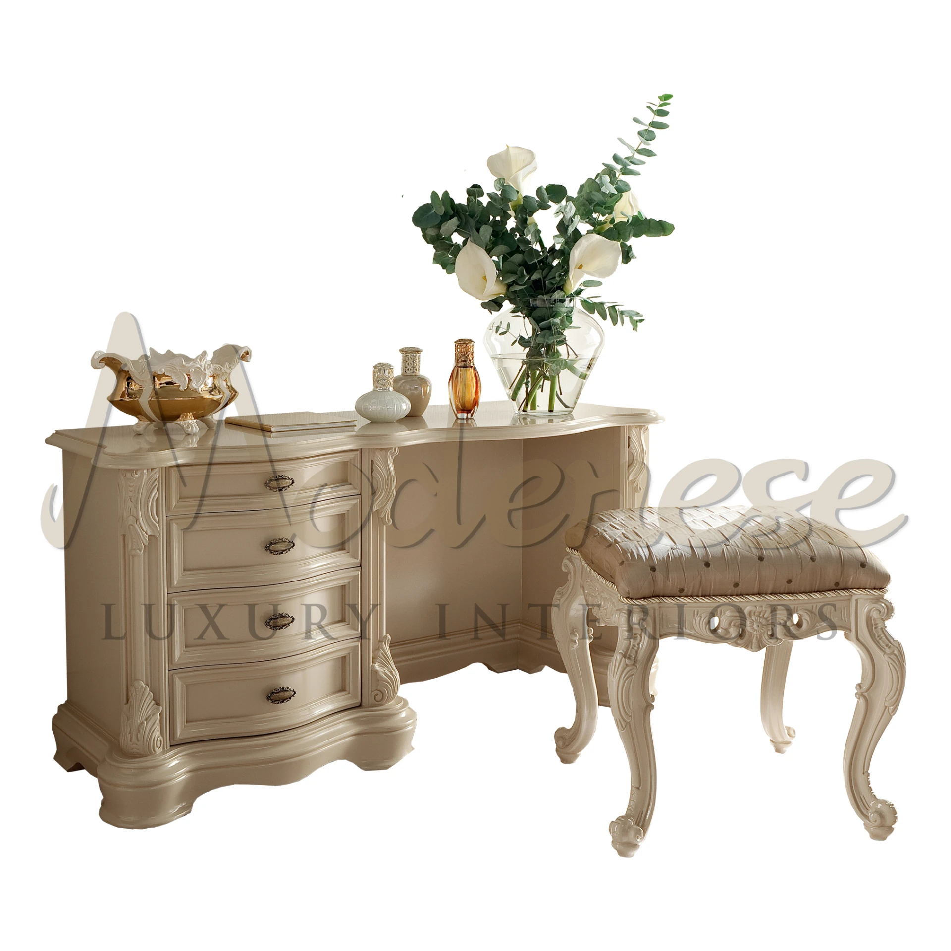 Beige French provincial dressing table with decorative carvings and a complementing stool with a patterned seat, adorned with a vase of flowers and perfume bottles.