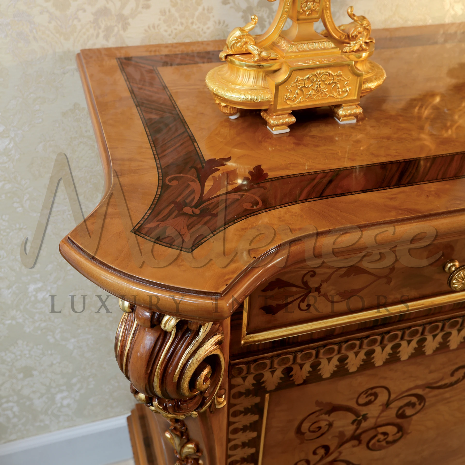 A close-up view of a Italian classic sideboard wooden cabinet with complex golden designs and a decorative golden object on top