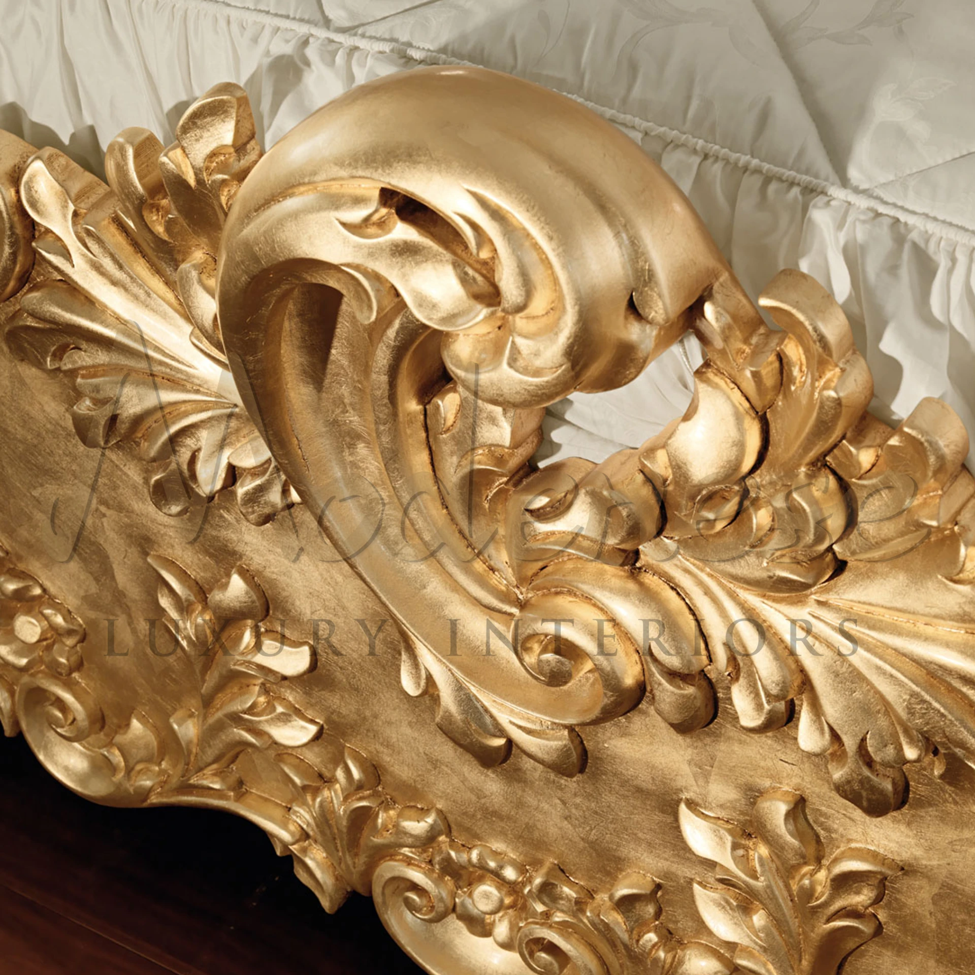 Close-up of a gold-leafed ornate carving on furniture created by Modenese Furniture Manufacturer, showcasing intricate craftsmanship and elegant swirls.